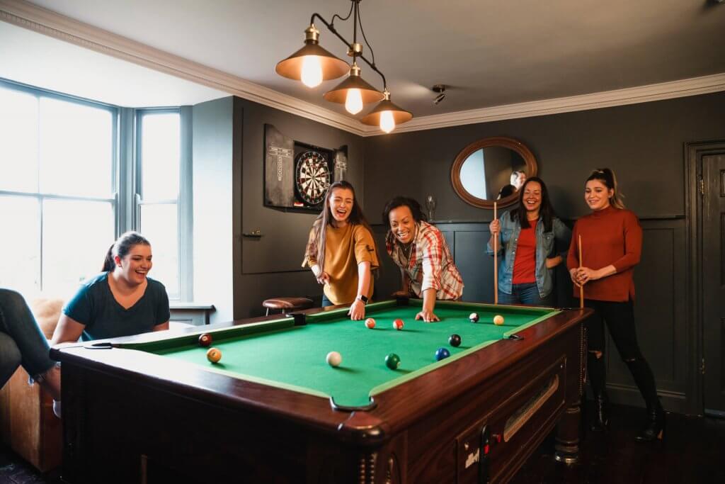 Small group of friends playing pool in a games room in a house
