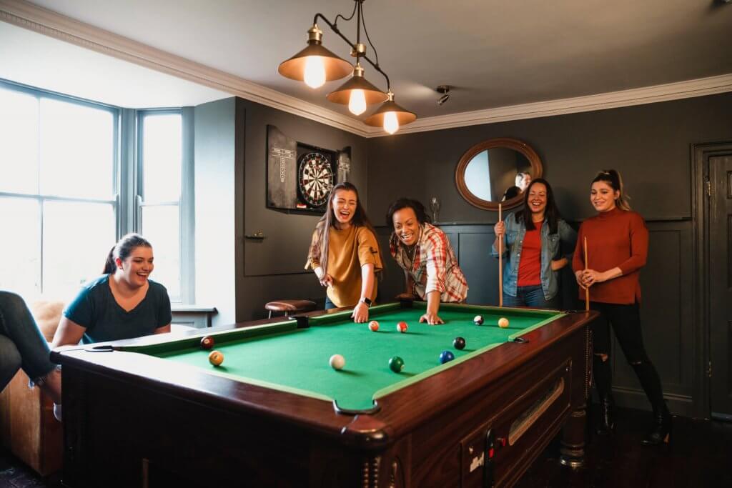 Small group of friends playing pool in a games room in a house