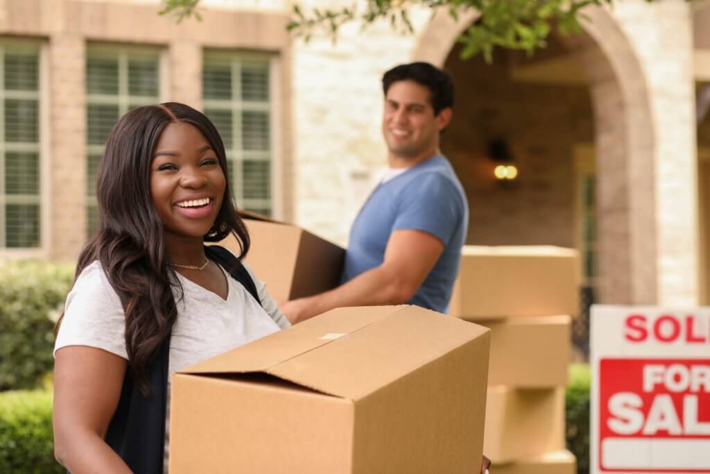 Excited young couple moves boxes into their new home.