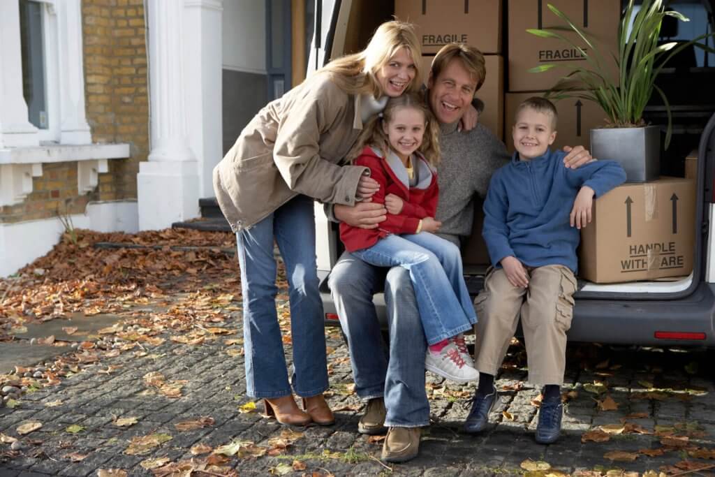 Family sitting in back of van with boxes