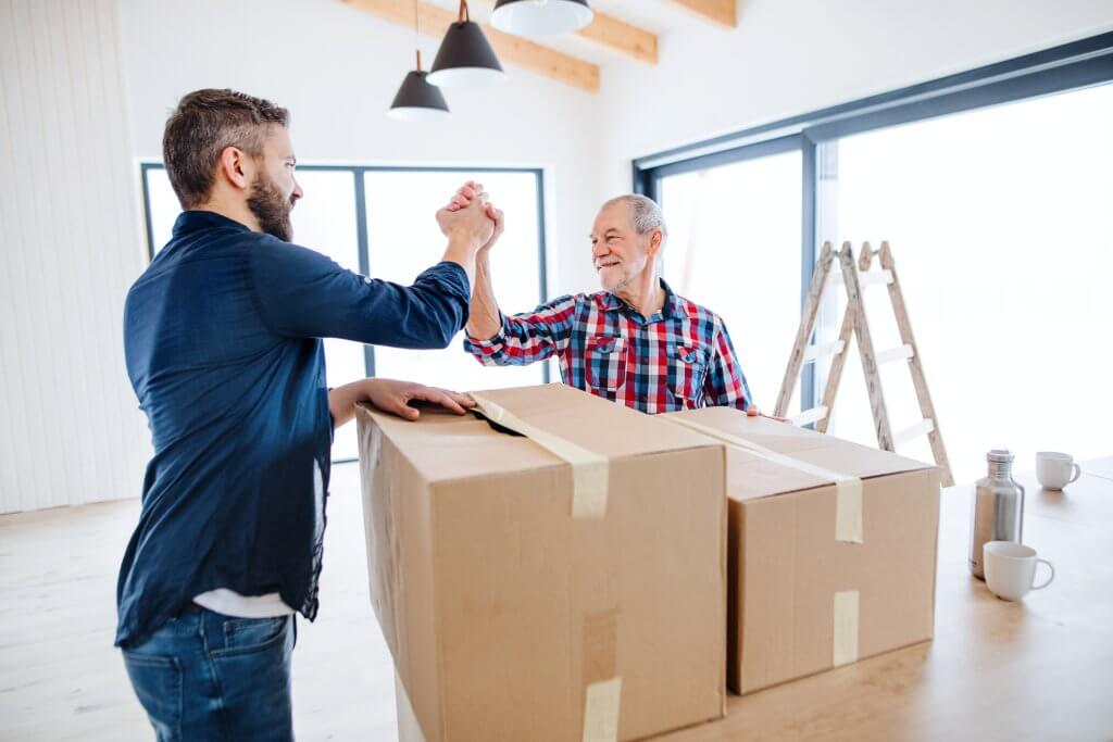 A mature man with his senior father furnishing new house