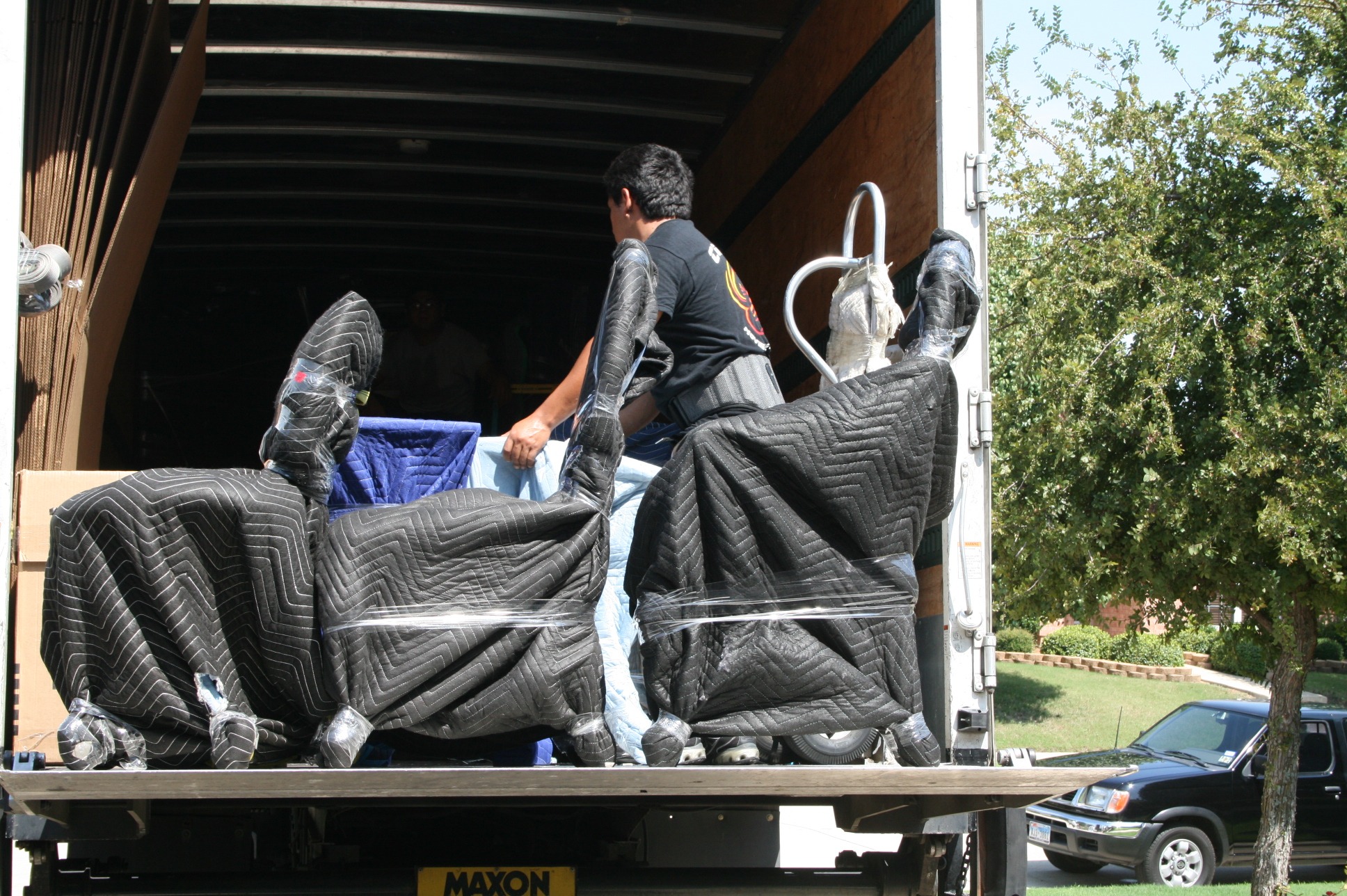 Mover loading blanket-wrapped and shrink-wrapped furniture onto a moving truck liftgate