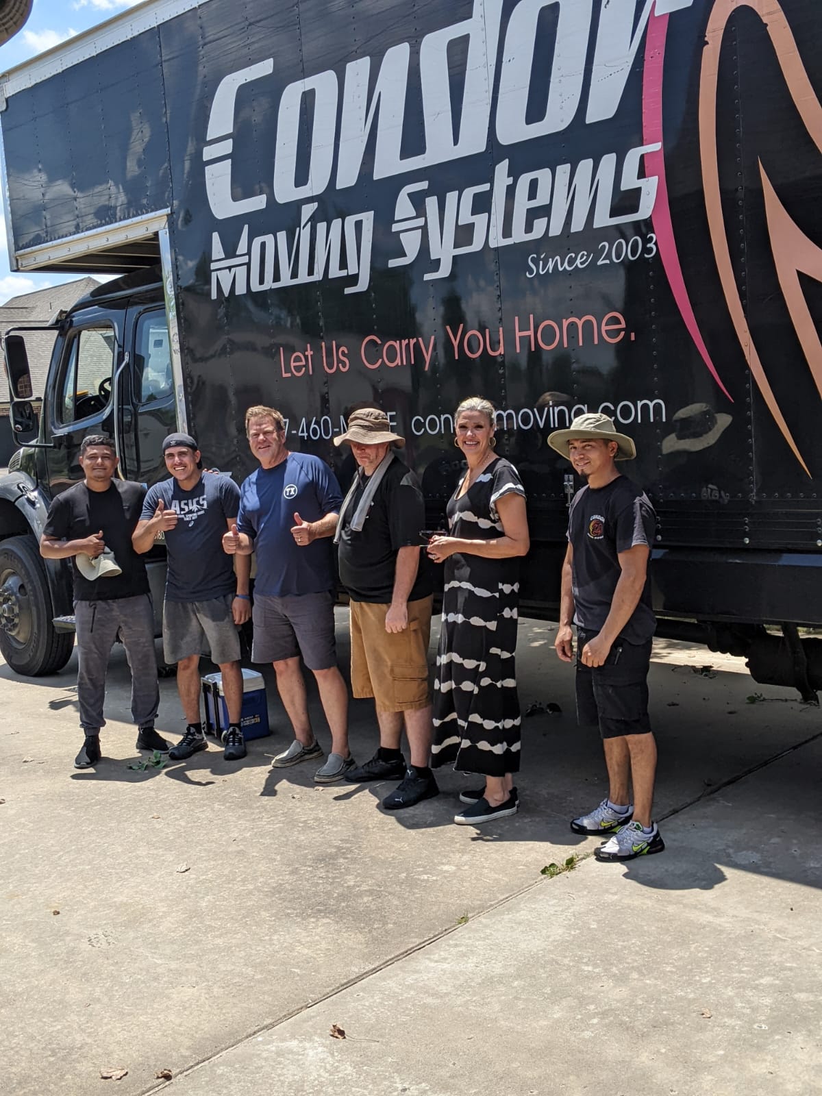 Condor Moving Systems crew standing with a customer in front of a Condor moving truck