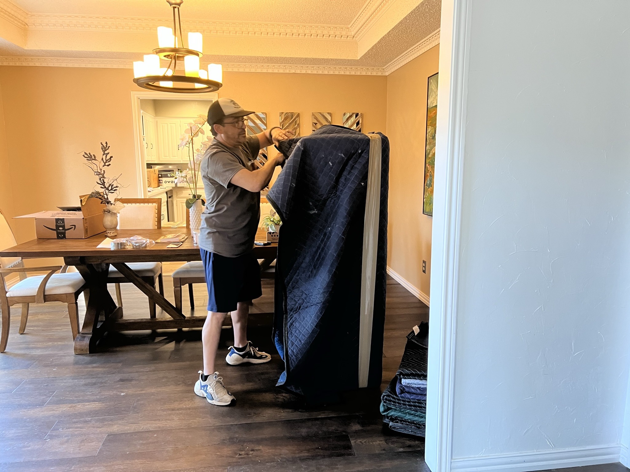 Condor mover wrapping a mattress in a moving blanket inside a customer's dining room