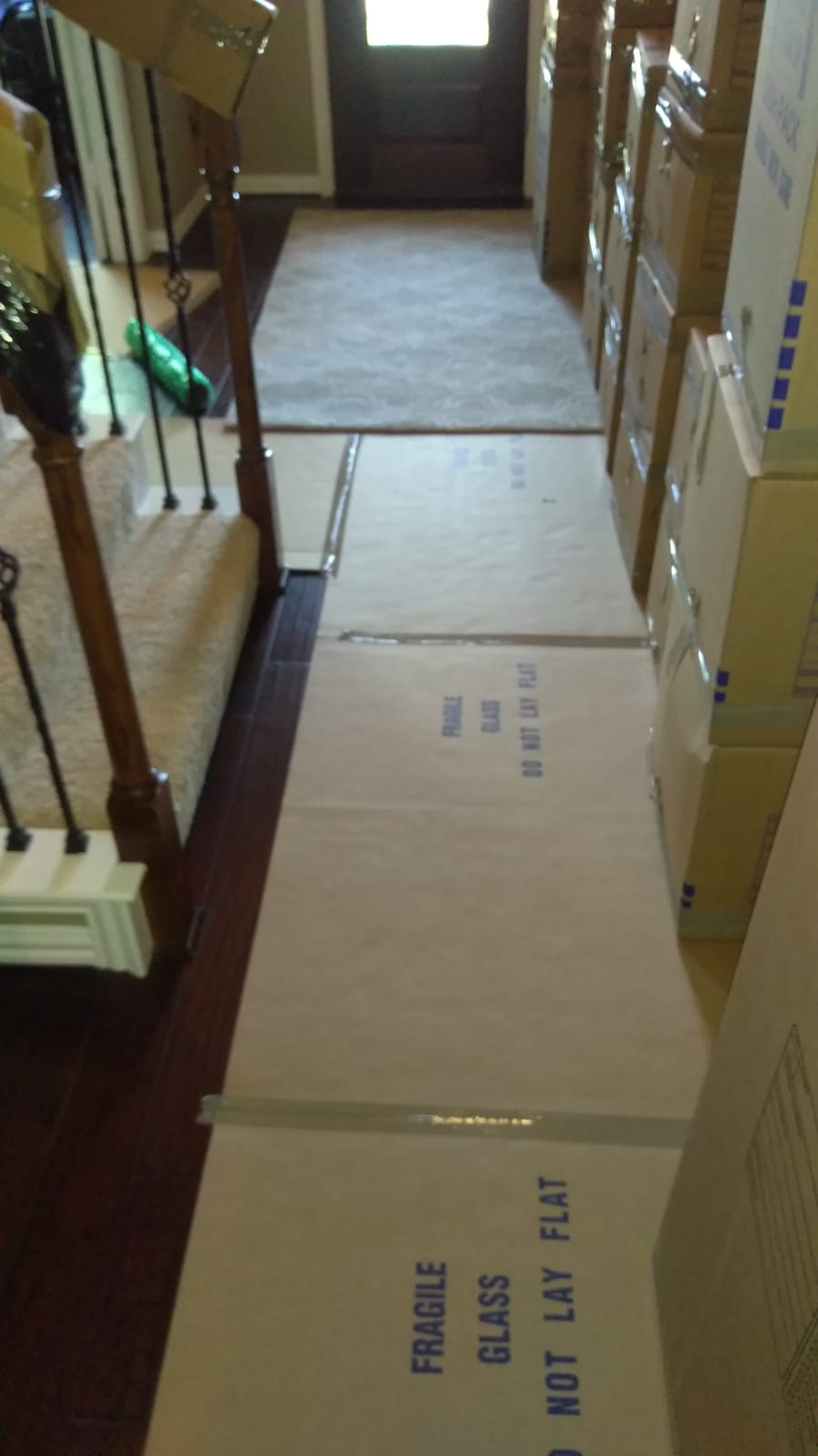 Floor protection laid along a hallway beside stacked packed boxes marked fragile