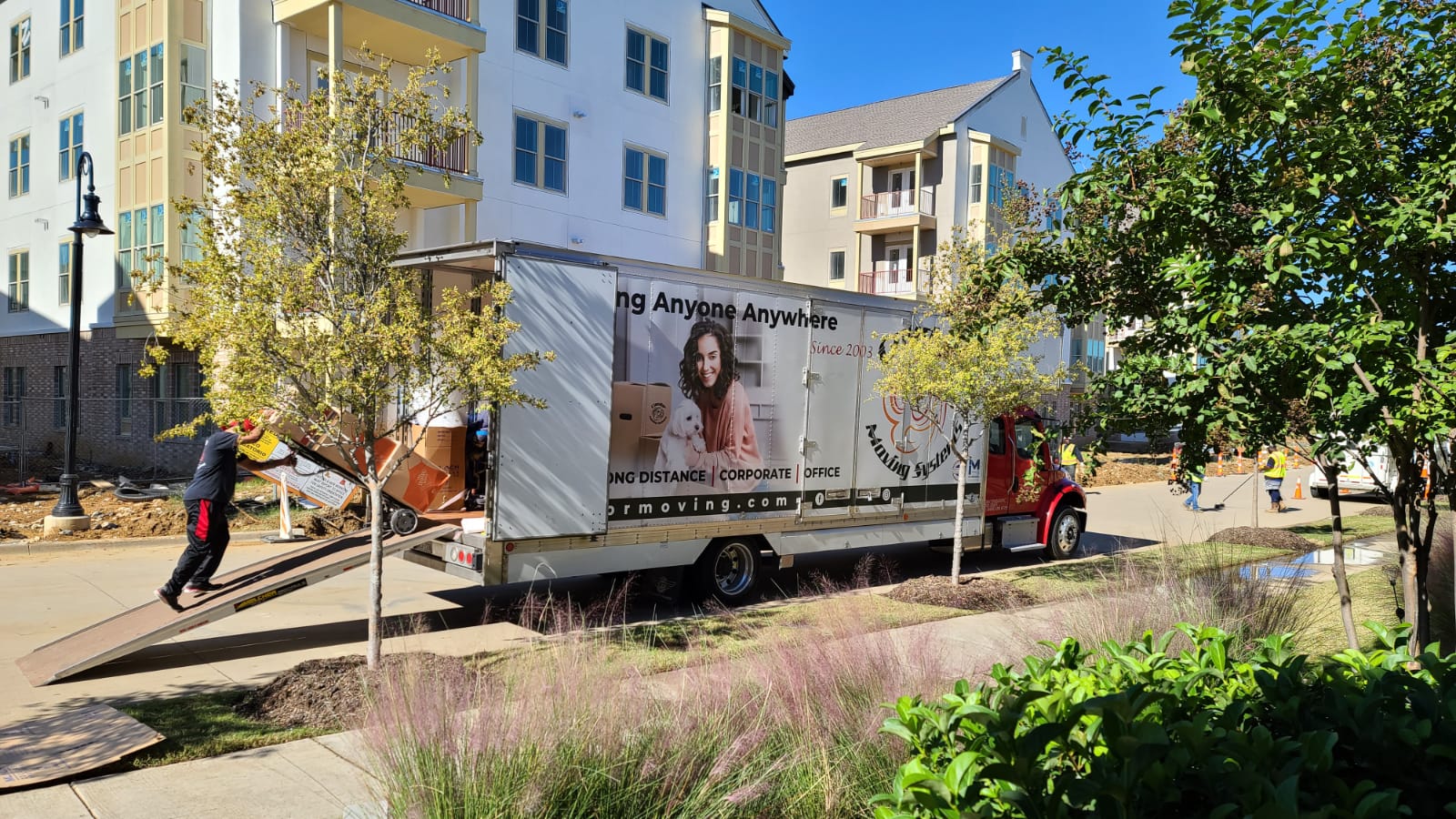 Condor moving truck with its ramp down loading at an apartment complex