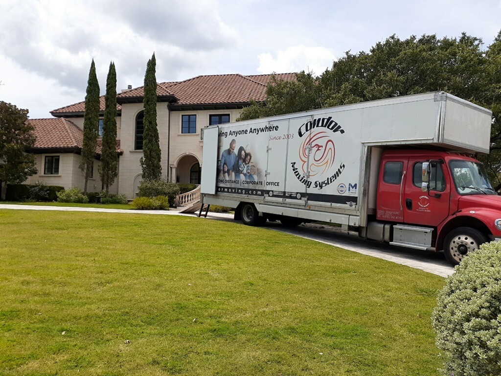 Condor Moving Systems truck parked in the driveway of a large home during a residential move